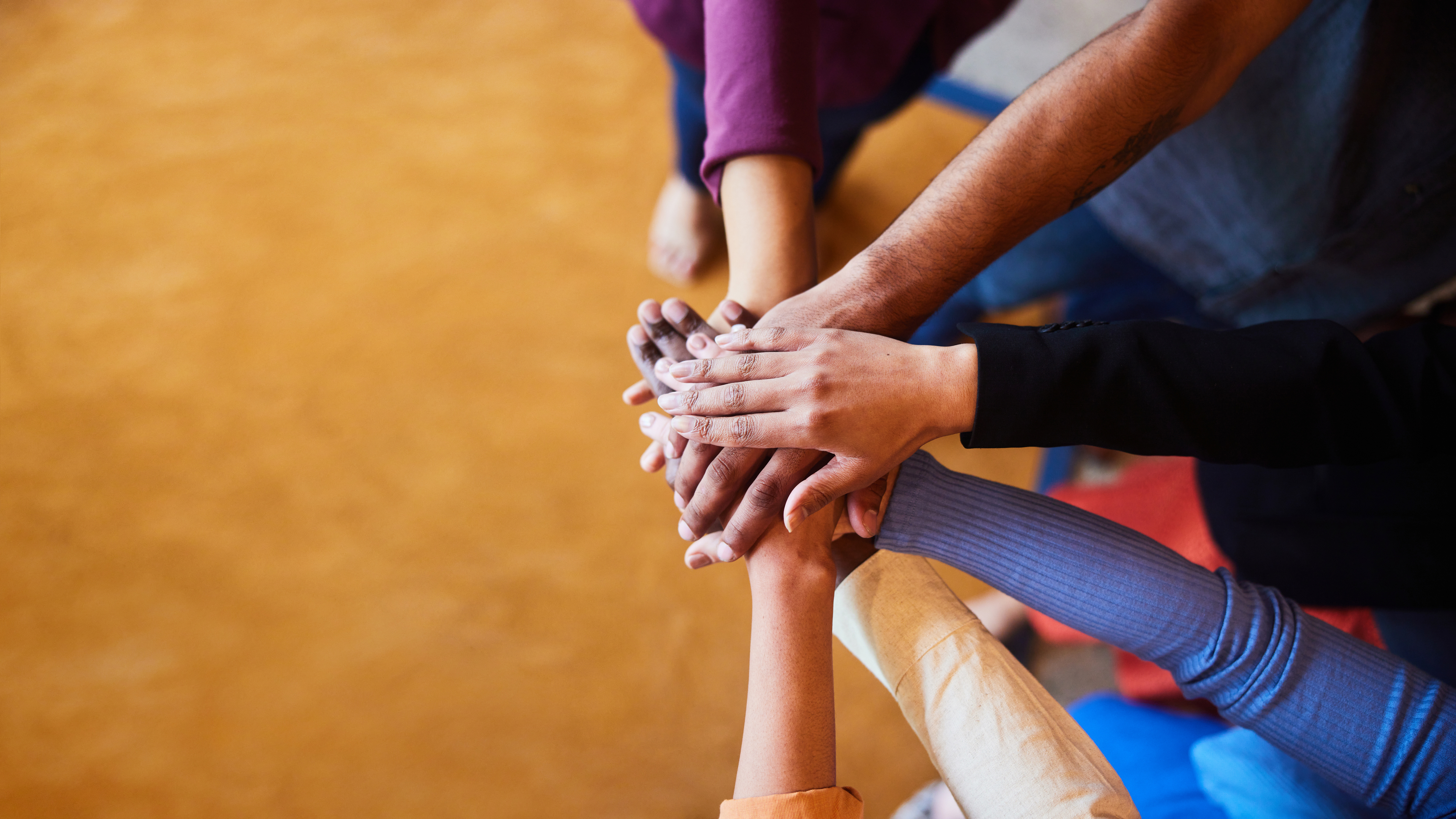 Close-up of extended hands stacked together in a gesture of teamwork and unity.